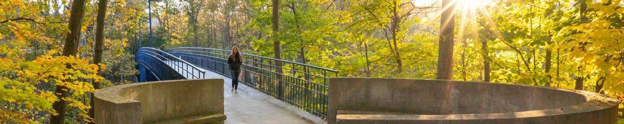 Student walking across Little Mack bridge in Allendale